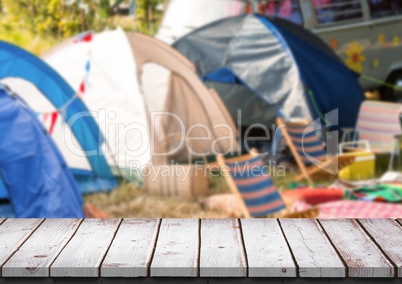 White wood table against blurry campsite