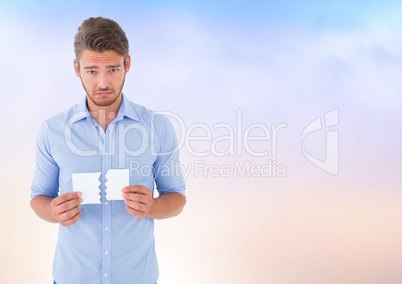 Sad man ripping paper against soft sky