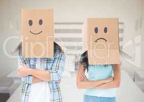 Couple with box heads sad and happy against bedroom