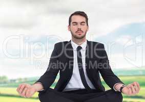 Businessman Meditating by green fields