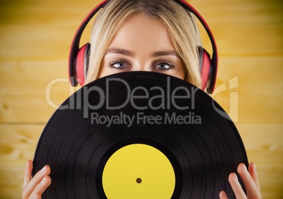 Woman with headphones and record against yellow wood panel