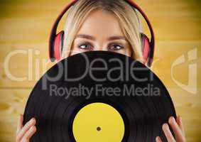 Woman with headphones and record against yellow wood panel