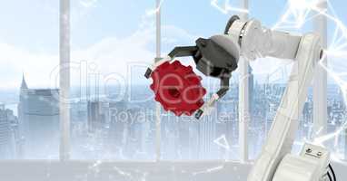 White robot claw holding red cog against white interface and window with skyline