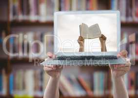 Hands with laptop showing hands with book against blurry bookshelf