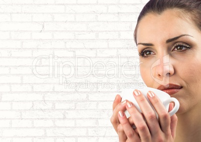 Close up of woman with white cup against white brick wall