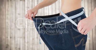 Woman with large pants and measuring tape against blurry wood panel