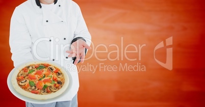 Chef with pizza against blurry orange wood panel