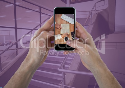 Hands with phone showing desk against stairs with purple overlay