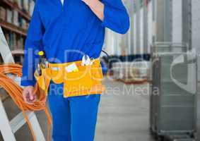 Handyman lower body with ladder against blurry warehouse
