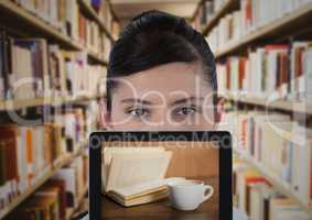 Woman with tablet showing book and coffee against blurry bookshelves