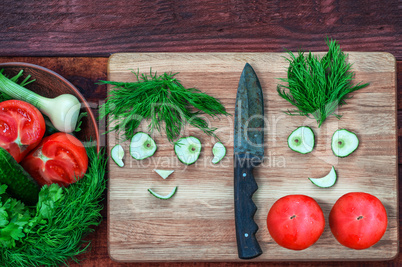 Fresh tomatoes and cucumber in a bowl and on a kitchen board