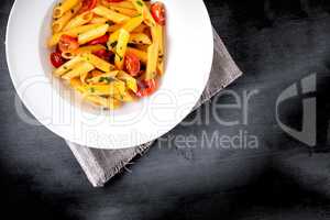 Penne with anchovy and tomato in a white plate.