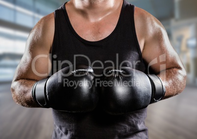 Man with boxing gloves mid sections against blurry gym