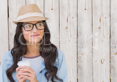 Woman with fedora and white coffee cup against white wood panel