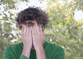 Upset stressed man hiding in hands under trees