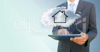 Business man with tablet and cloud with house against blue background
