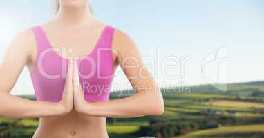 Woman praying yoga Meditating in front of green hills
