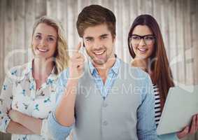 Three people with phone and laptop against blurry wood background