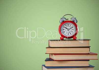 Pile of books and clock against green background