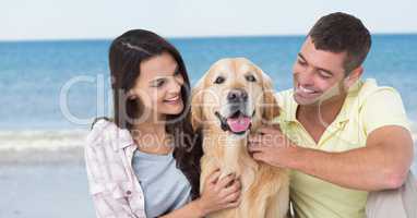 Couple with dog against blurry beach
