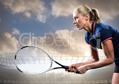 Tennis player with racket outstretched against stadium and sky with clouds