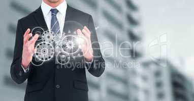 Business man with white cog graphics against blurry building