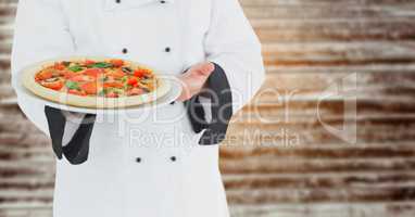 Chef with pizza against blurry wood panel