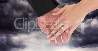 Wedding couple holding hands in front of dark clouds