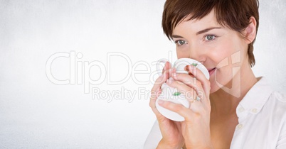Woman drinking from mug against white wall