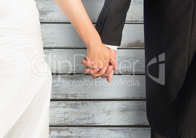 Wedding couple holding hands against wood