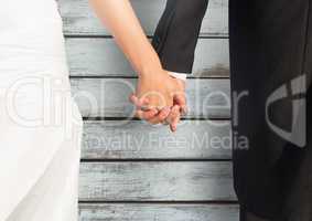 Wedding couple holding hands against wood