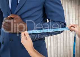 Man in suit mid section being measured against blurry wood panel