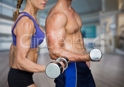Man and Woman mid sections weightlifting in blurry gym