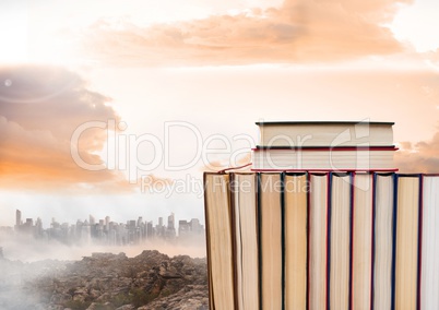 Books stacked by distant city and clouds