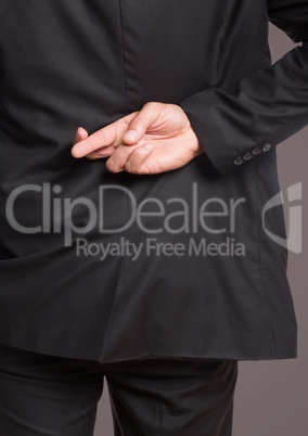 Back of business man with fingers crossed against brown background
