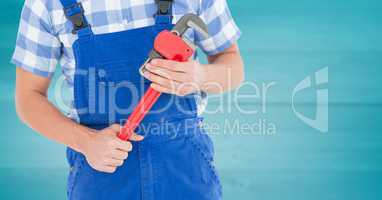 Handyman with red wrench against blurry blue wood panel