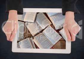 Hands with tablet on navy table showing open books