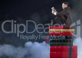 Businessman sitting on Books stacked by clouds