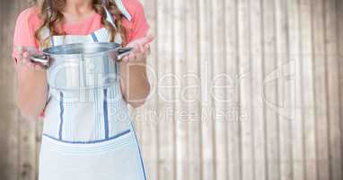 Woman in apron with pan against blurry wood panel