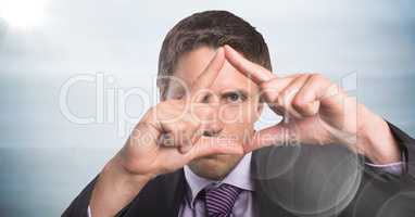 Close up of business man making triangle with flare against blurry grey wood panel