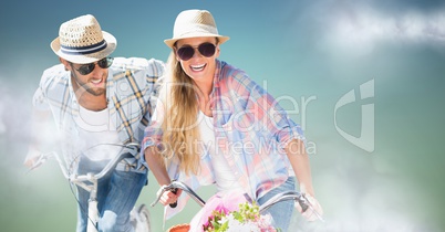 Couple on bikes against blue green background with clouds