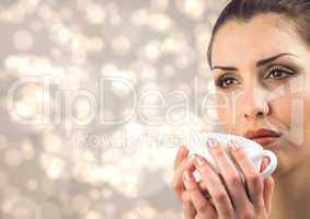 Close up of woman drinking from white cup against cream bokeh