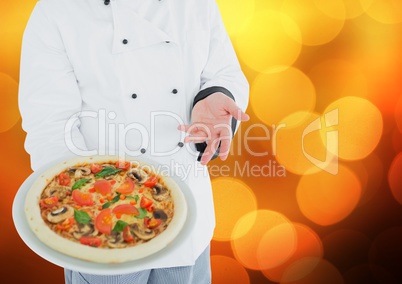 Chef with pizza against blurry orange bokeh