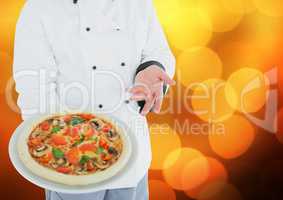 Chef with pizza against blurry orange bokeh