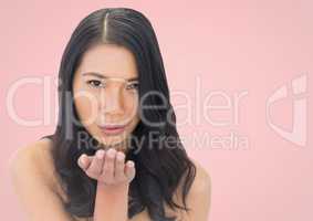 Woman blowing kiss against pink background