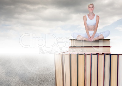 Woman meditating  sitting on Books stacked by grey cloudy sky