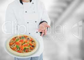 Chef with pizza against blurry grey stairs