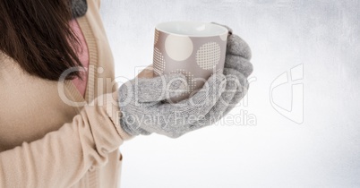 Close up of woman holding polka dot mug against white wall