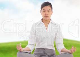 Businesswoman Meditating by green hill