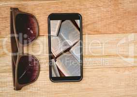 Sunglasses and phone showing open books